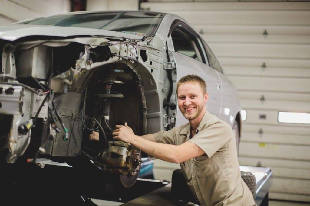 Auto repair technician working on vehicle suspension in a professional garage setting, showcasing expertise and commitment to quality service at Barry's Paint Shop Stevens.
