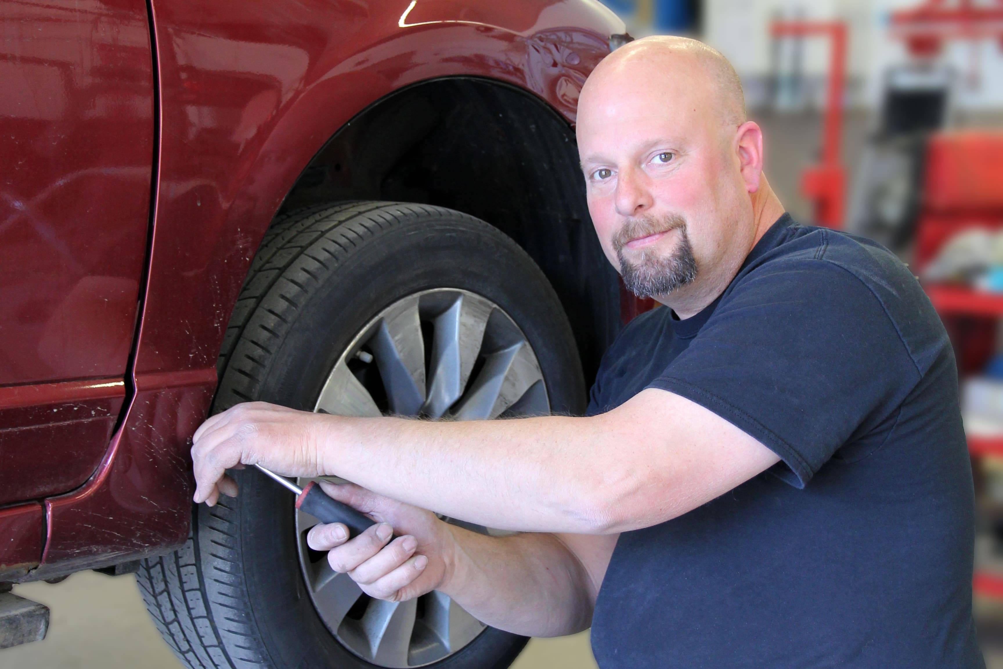 Auto body technician working on a maroon vehicle at Barry's Paint Shop, demonstrating collision repair expertise and attention to detail.
