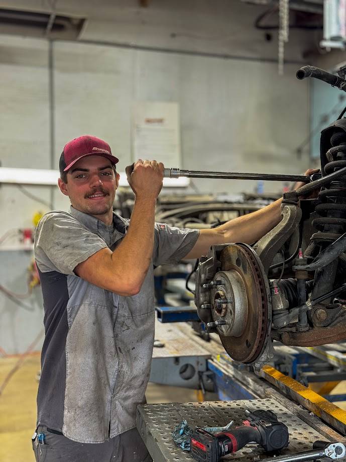 Technician working on vehicle suspension system at Barry's Paint Shop, showcasing expertise in automotive repairs and commitment to quality service.
